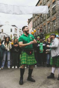Photographie de voyage d'un irlandais en kilt danse au milieu d'une foule qui l'entoure. Des photographies de voyage originales, sincères et esthétiques qui subliment vos destinations.