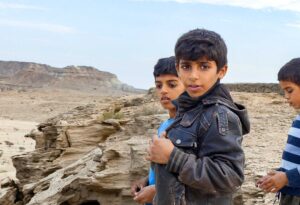 Des photographies de voyage originales, sincères et esthétiques qui subliment vos destinations. Iran : jeunesse plurielle. Trois garçons iraniens dans le désert en haut d'une falaise, dans le golfe persique.
