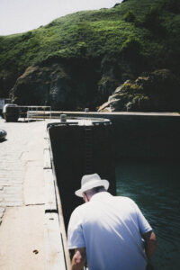 Un homme de dos dans le port de l'île de Sark. Des photographies de voyage originales, sincères et esthétiques qui subliment vos destinations.