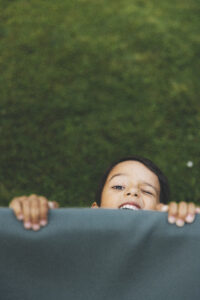 Un jeune garçon joue et se cache. Du naturel à la mise en scène : des portraits adaptés à votre univers.
